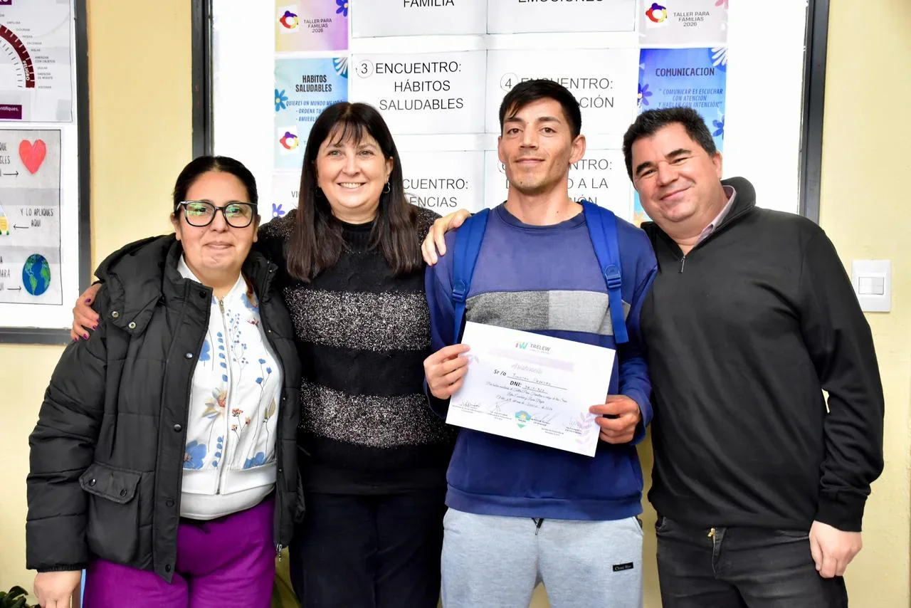 Cuatro personas posan sonrientes en el CIC de Menfa; un hombre sostiene un certificado de los talleres de crianza.