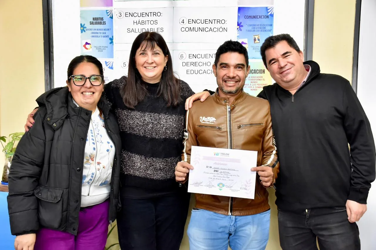 Cuatro personas posan sonrientes en el CIC Menfa; un hombre sostiene un certificado de los talleres de crianza.