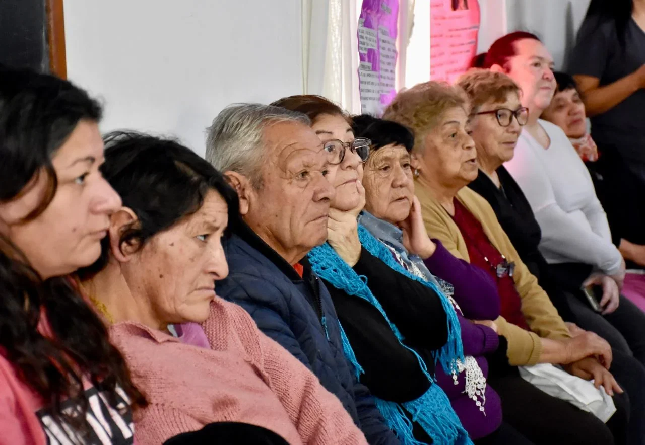 Grupo de adultos mayores y acompañantes sentados escuchando una jornada de sensibilización en Trelew.