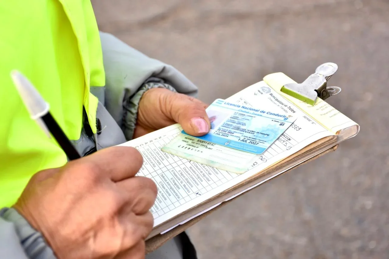 Operativo de tránsito en Trelew: agente municipal revisando una licencia de conducir sobre una planilla de control.