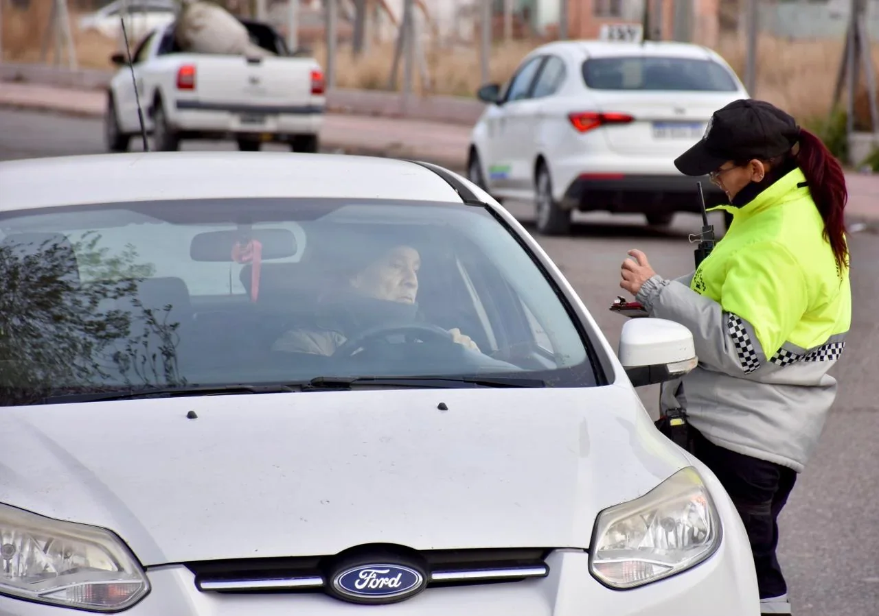 Control de tránsito en Trelew: agente municipal con chaqueta reflectante supervisa a conductor en auto blanco.
