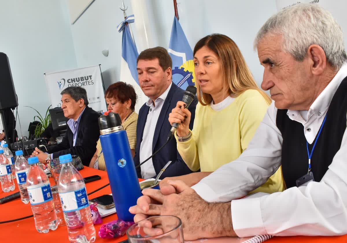 Una mujer con suéter amarillo habla por micrófono en una mesa principal junto a autoridades