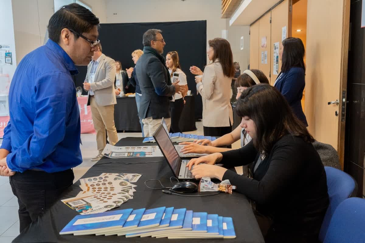 Un hombre con camisa azul consulta en el stand de acreditación e información