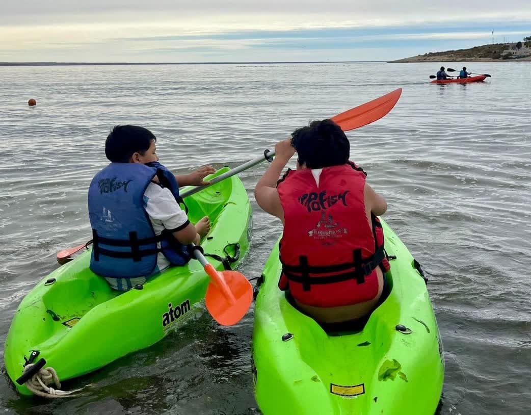 Puerto Madryn expuso su modelo de Turismo Deportivo Oceánico Sostenible ante estudiantes latinoamericanos Dos personas navegando en kayaks verdes con chalecos salvavidas