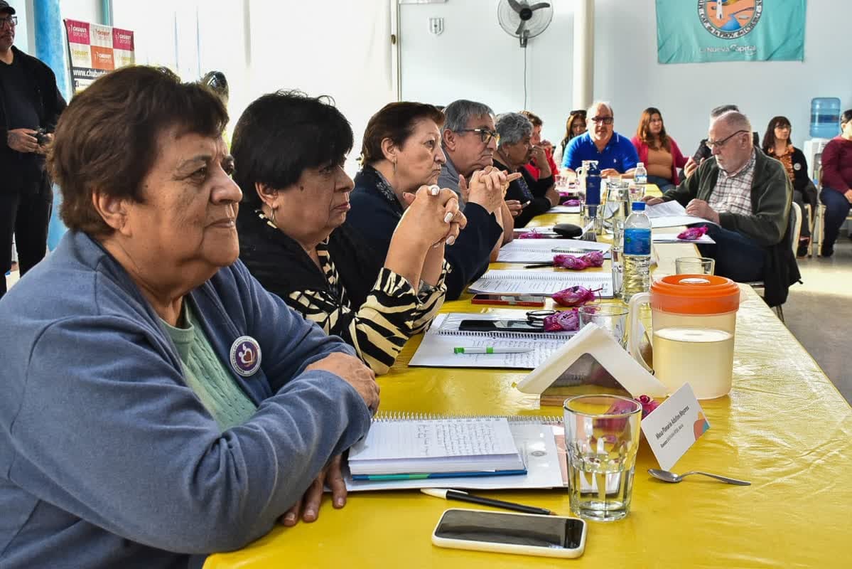 Grupo de adultos mayores sentados a una larga mesa de trabajo